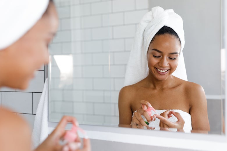 A woman applying cream in the mirror.